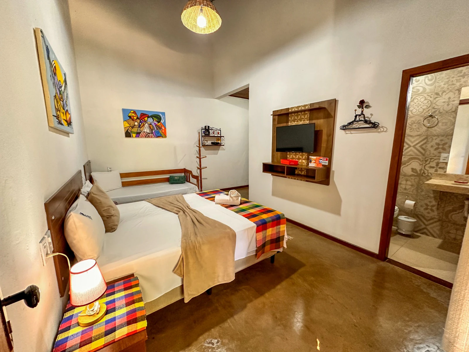Quarto do flat com cama, TV e banheiro privativo