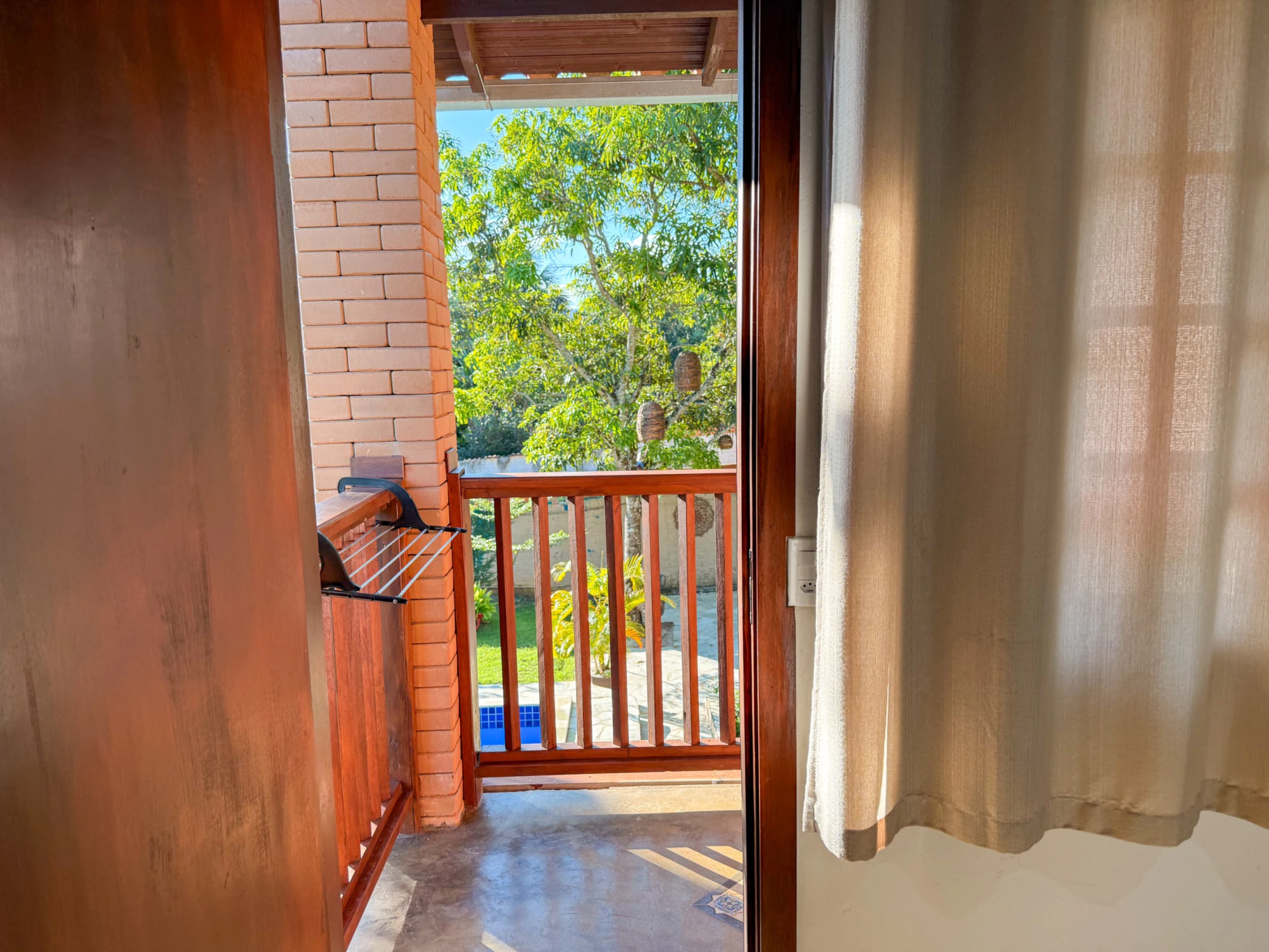 Varanda superior do flat com vista para o jardim e a piscina