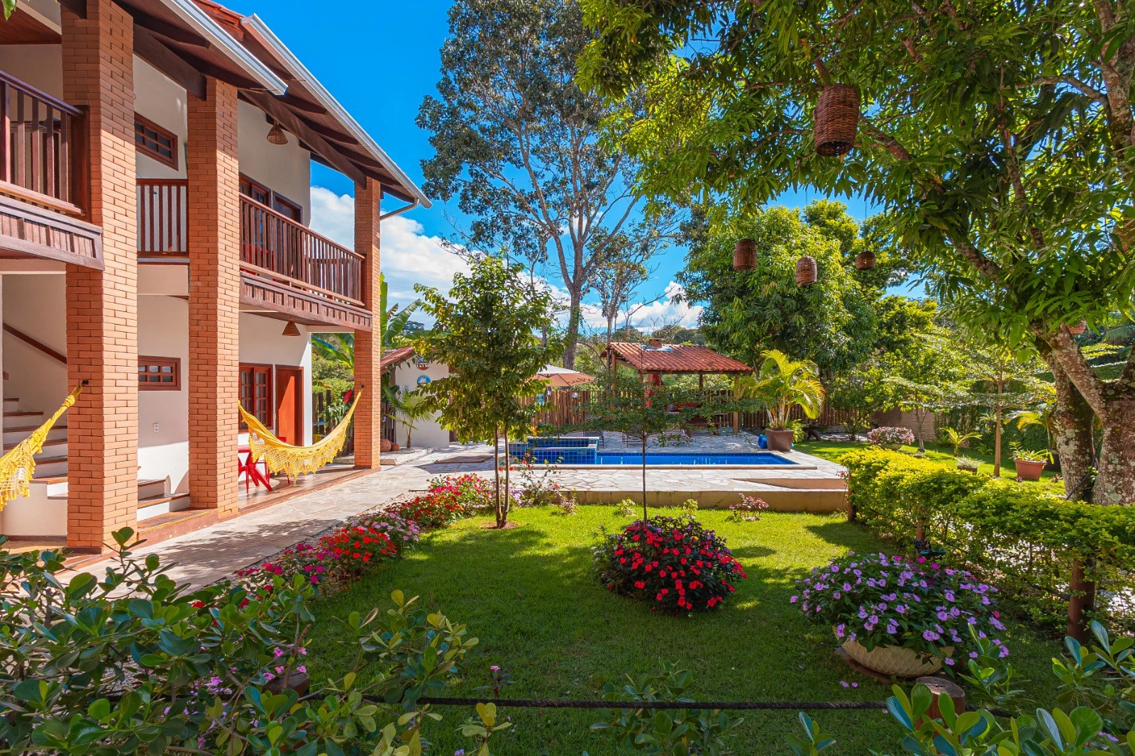 Jardim florido com piscina aquecida e fachada dos flats
