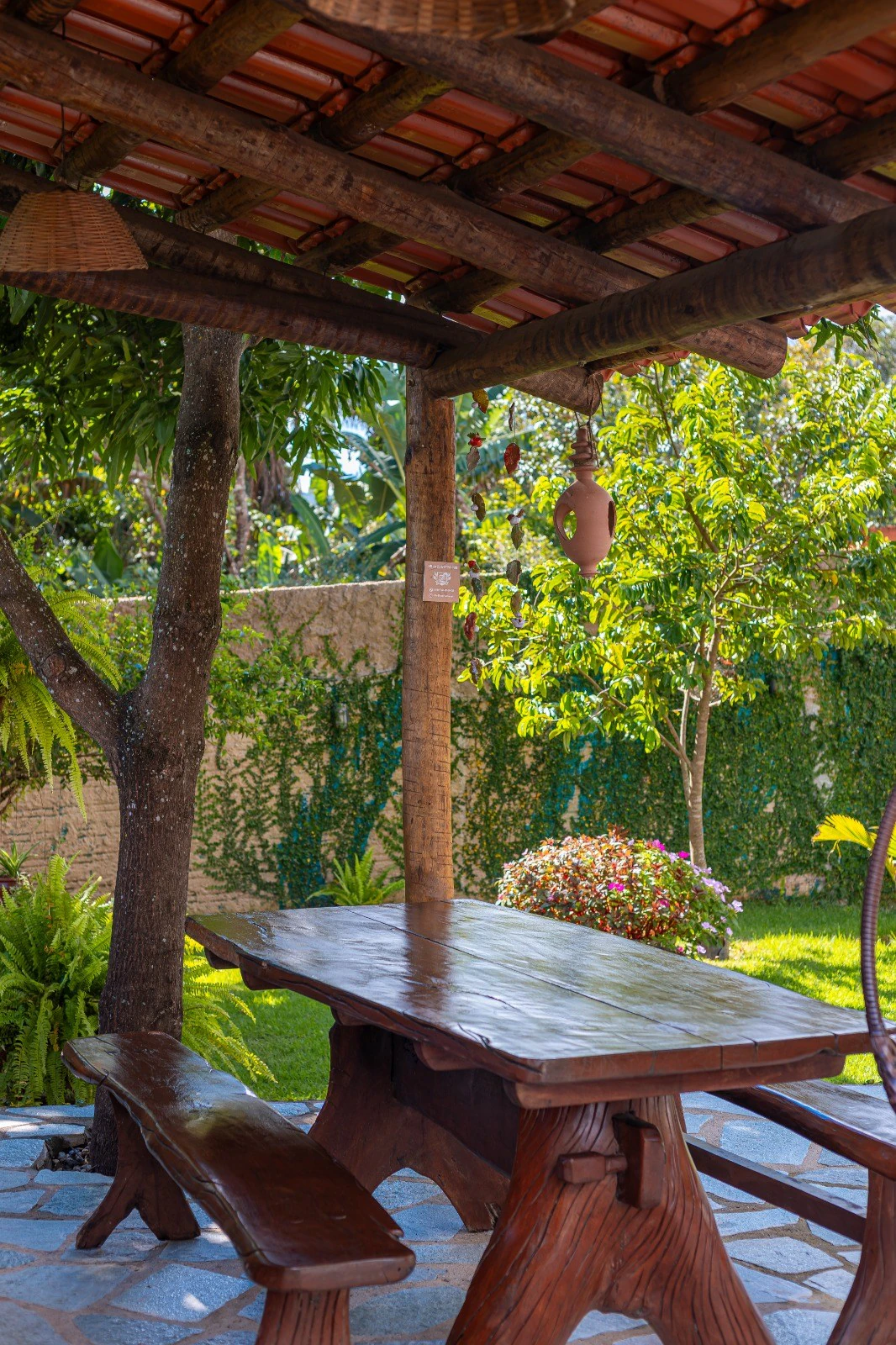 Mesa de madeira no quiosque de convivência cercado pelo jardim